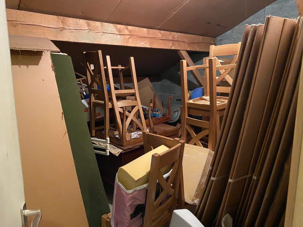 Grenier encombré avec chaises empilées.