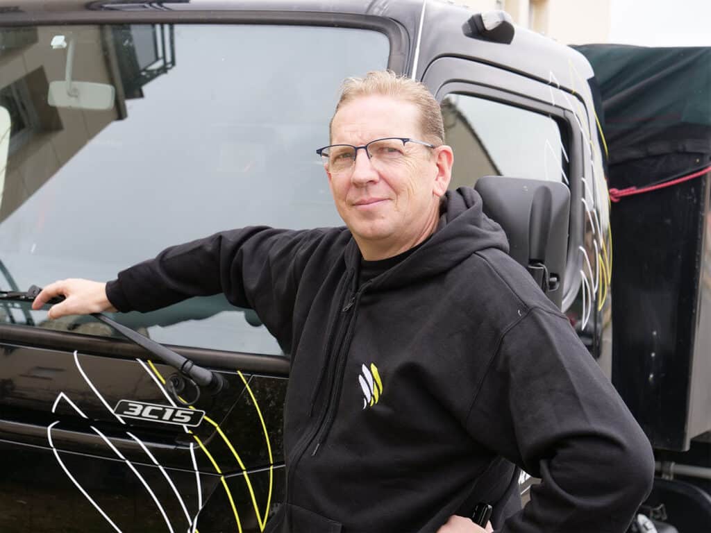 Homme devant un véhicule noir décoré.