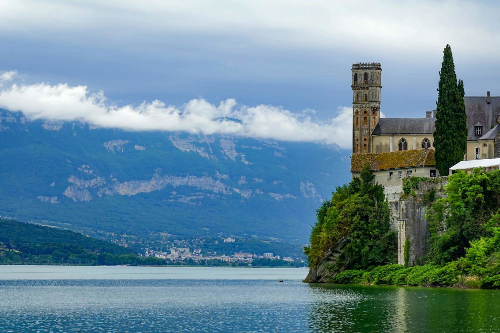 Château au bord d'un lac et montagnes.