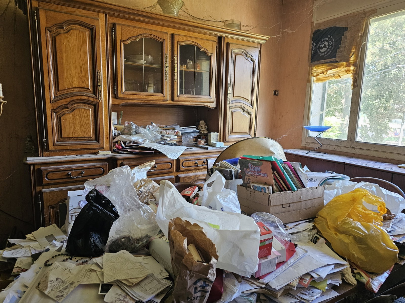 Salle à manger encombrée de papiers et objets divers.