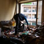 Personne nettoyant une pièce encombrée de déchets.