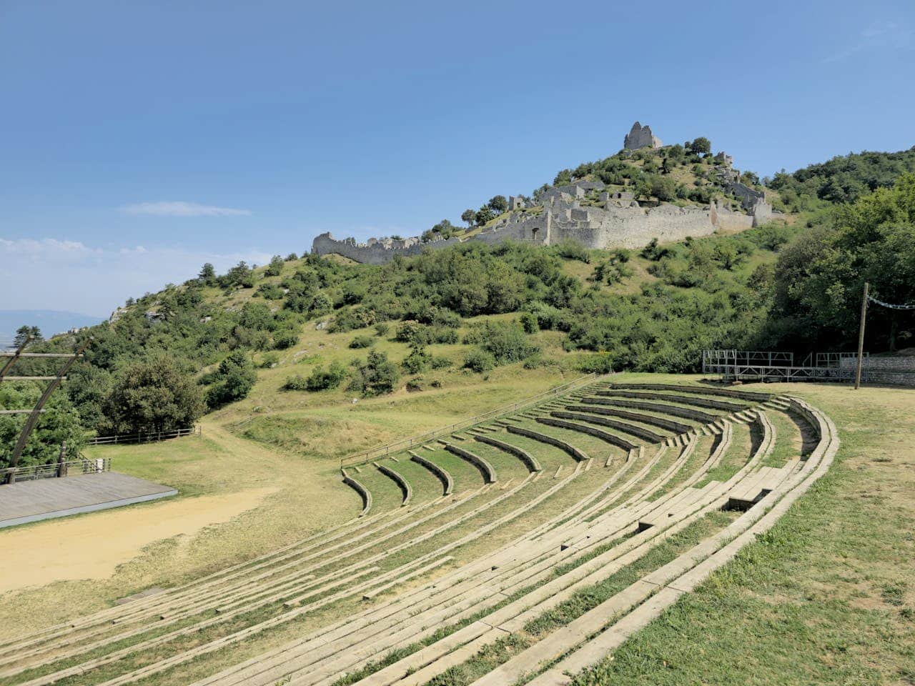 Amphithéâtre ancien avec ruines médiévales en arrière-plan.