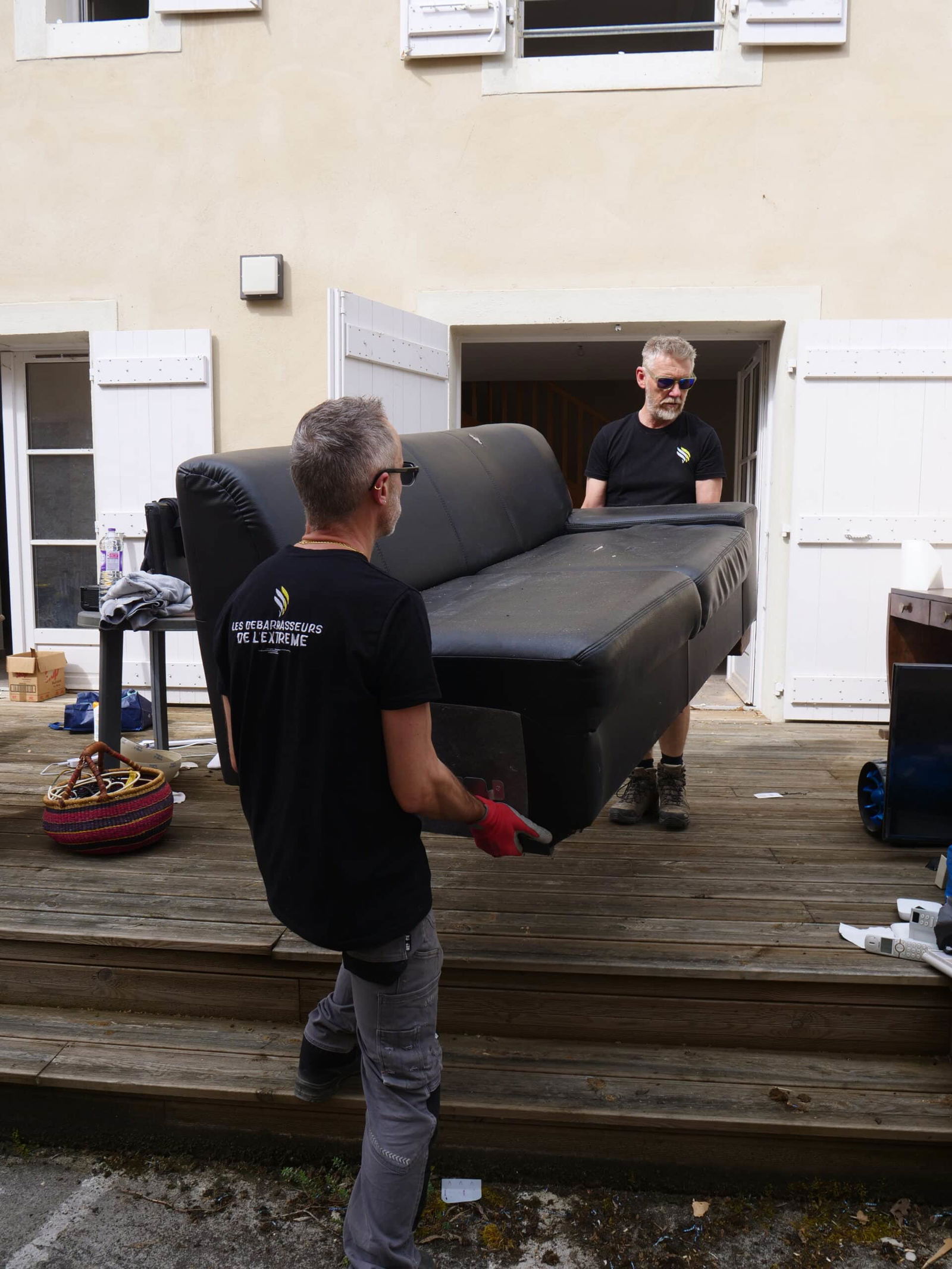 Deux hommes déménageant un canapé noir.
